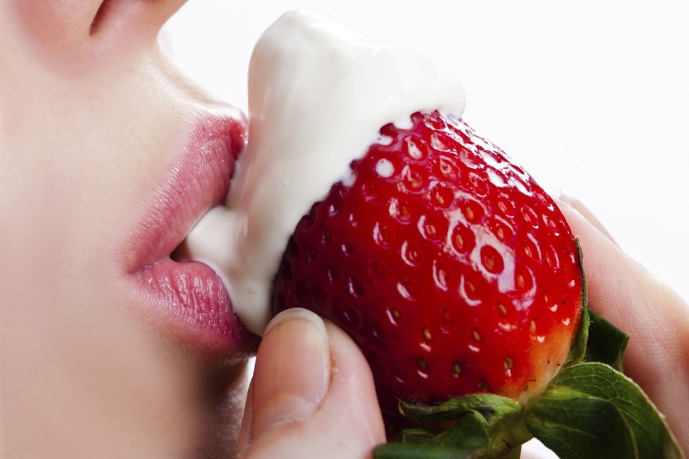 Une fille mange des fraises avec de la crème